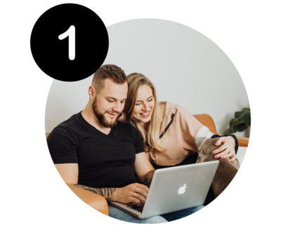 a happy man and woman looking at a laptop computer while sitting on a couch